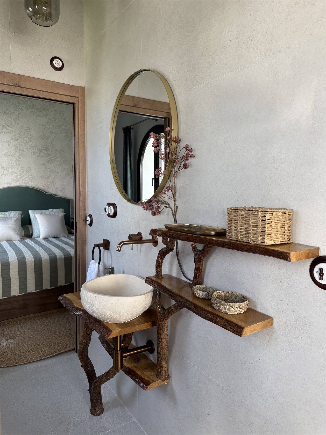 Baño artesanal con lavabo de piedra y el dormitorio al fondo